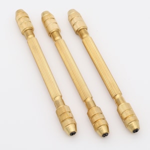May include: Three gold-colored metal hand-held drill bits with a knurled handle and a pointed tip.