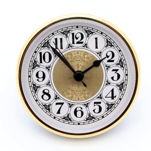 May include: A white clock face with black Roman numeral hour markers and black hands. The clock face has a gold-colored center with a decorative pattern. The clock is surrounded by a gold-colored frame.