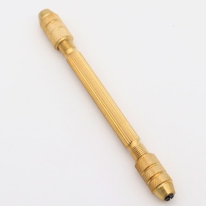 May include: A gold-colored metal hand drill with a ribbed handle and a chuck at each end.