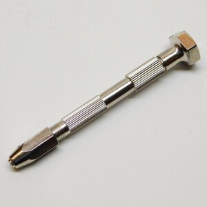 May include: A small, silver-colored pin vise with a hexagonal head and a ribbed handle. The tool is designed for precision work, with a tapered end for holding small drill bits or other accessories. The vise is shown against a white background.