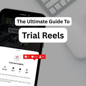 Może przedstawiać: Smartfon wyświetla aplikację społecznościową z tekstem "The Ultimate Guide To Trial Reels". Ekran pokazuje statystyki, w tym polubienia, komentarze i udostępnienia. Klawiatura, mysz i notatnik znajdują się na białej powierzchni.
