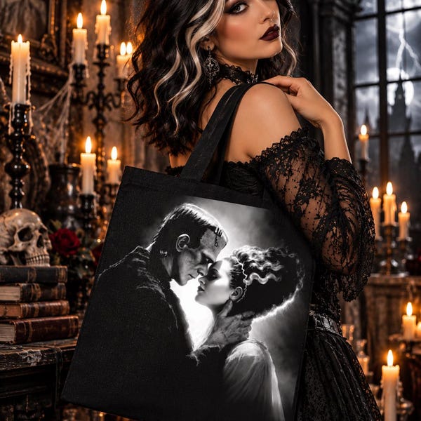 Könnte beinhalten: Eine schwarze Tragetasche mit einem kontrastreichen, schwarz-weißen Grafikdruck von Frankensteins Monster und seiner Braut in einer intimen, einander zugewandten Pose. Die Tasche hat stabile Schulterriemen und eine rechteckige Form.