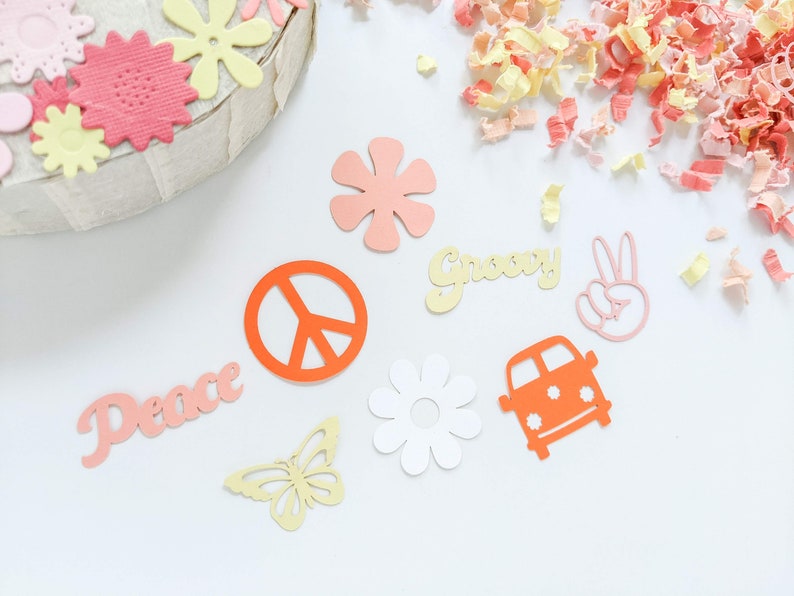 May include: A collection of paper cutouts in various shapes and colors, including peace signs, flowers, butterflies, and a van. The words "Peace" and "Groovy" are also included.