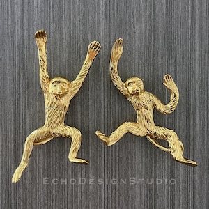 May include: Two gold monkey figurines, one hanging from a branch and the other running, with a textured surface.