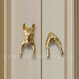May include: Two gold-toned metal door knobs shaped like a French bulldog. One knob is facing forward and the other is facing backward.