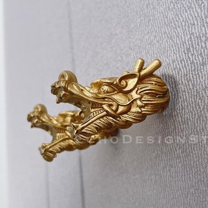 May include: A pair of gold dragon head door handles. The handles are detailed and have a textured finish.