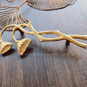 May include: Gold-toned cabinet hardware with a lotus flower design. The hardware features a stylised branch with two lotus flower pulls.