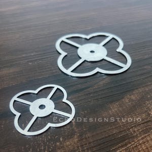 May include: Two silver-coloured metal cutting dies in a four-lobed clover shape. Each die features a central circular hub with four thin spokes extending to the outer edge. The text ECHODESIGNSTUDIO is visible in the lower right corner of the image.