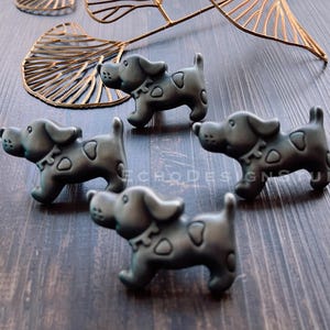 Może przedstawiać: Cztery czarne metalowe gałki do szafek w kształcie psa z kropkowanym wzorem.