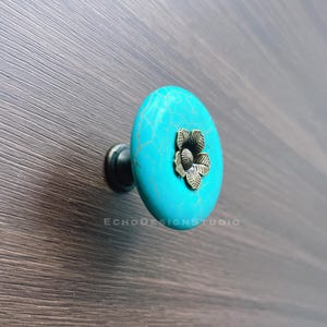 May include: Turquoise blue cabinet knob with a decorative gold flower design.