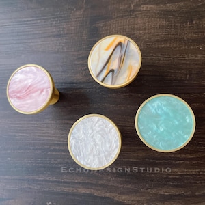 May include: Four decorative hooks with a gold finish and different marbled patterns. The hooks are pink, white, blue, and brown.