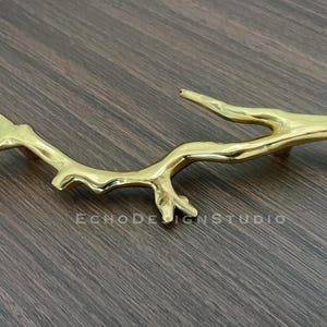 Puede incluir: Herraje de armario de metal dorado en forma de rama de árbol estilizada.