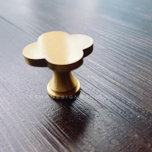 May include: A gold-toned metal cabinet knob with a four-leaf clover design.