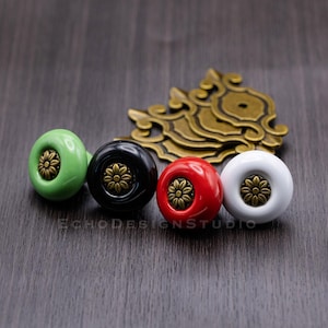 May include: Four ceramic cabinet knobs with a floral design. The knobs are green, black, red, and white.
