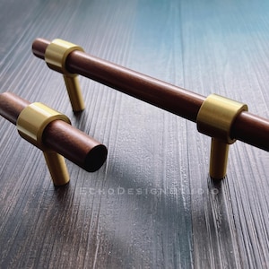 Puede incluir: Dos tiradores de armario de madera con detalles en latón. El tirador más grande mide 12,7 cm de largo y el más pequeño mide 7,6 cm de largo.