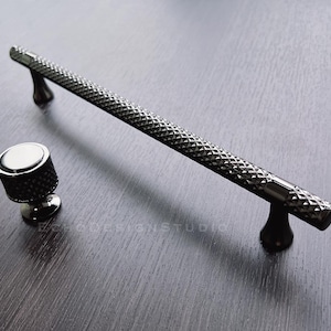 May include: A set of two black metal cabinet knobs with a diamond pattern. The larger knob is a pull handle and the smaller knob is a round knob.