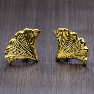 May include: A pair of gold-tone earrings shaped like ginkgo leaves.