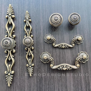May include: Set of antique gold cabinet hardware with ornate floral designs. Includes two drawer pulls, two knobs, and two cabinet pulls.