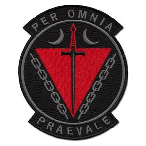 May include: Embroidered patch with a black background and a red triangle. A black sword is centered on the red triangle. The patch has the words "PER OMNIA" and "PRAEVALE" in white lettering. Two crescent moons and a chain border the triangle.