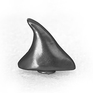 May include: A small, gray, metal shark fin ornament. The fin is pointed and has a smooth, polished surface.