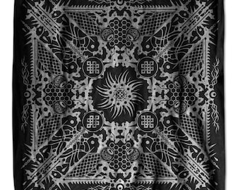 May include: Black bandana with a detailed white geometric design. The square cloth features a central sunburst pattern surrounded by repeating shapes, chains, and intricate lines. The overall design is symmetrical and intricate.