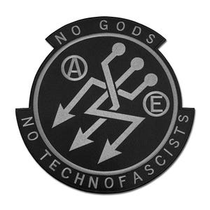 May include: Black patch with silver text and design. The patch reads "NO GODS" at the top and "NO TECHNOFASCISTS" at the bottom. The center features a stylized design with arrows and the letters "A" and "E".