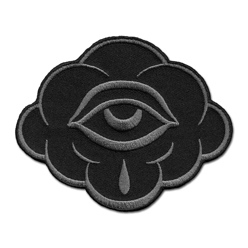 K&ouml;nnte beinhalten: Schwarzer, gestickter Aufn&auml;her mit einem stilisierten Auge in einer Wolkenform. Das Auge und die Wolke sind grau umrandet, mit einer tropfenf&ouml;rmigen Form unter dem Auge. Geeignet f&uuml;r Kleidung oder Accessoires.