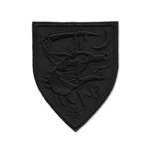 May include: Black embroidered patch in the shape of a shield with a stylised scorpion design.