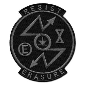 May include: Black embroidered patch with the words "RESIST" and "ERASURE" in arched banners. The patch features a central circular design with arrows, a downward-pointing arrow, an "E", and an hourglass shape.