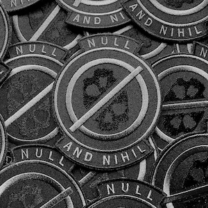 K&ouml;nnte beinhalten: Eine Ansammlung von schwarz-wei&szlig;en, gestickten Aufn&auml;hern. Jeder runde Aufn&auml;her zeigt ein Totenkopf-Design mit einem Strich durch ihn und den Worten "NULL AND NIHIL". Die Patches haben ein detailliertes, gesticktes Aussehen.