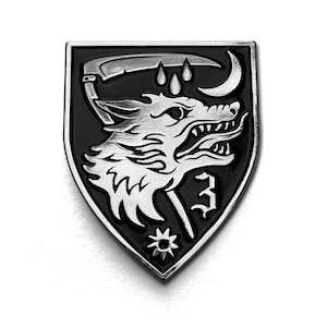 Könnte beinhalten: Ein silber-schwarzer, schildförmiger Ansteckpin mit einem Wolfskopf, einer Sense, einem Halbmond und stilisierten Tropfen. Der Pin hat ein detailliertes Design mit einem Stern und der Zahl 3.