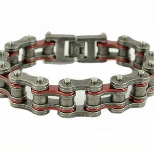 May include: A silver chain bracelet with red accents. The bracelet is made of linked metal pieces.