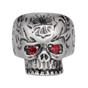 May include: A silver skull ring with red gemstone eyes and intricate floral designs.