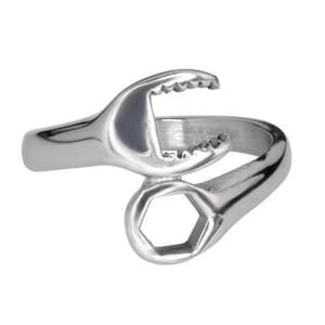 May include: A silver-colored ring shaped like a wrench. The ring features a wrench head with a toothed jaw and a hexagonal opening. The ring is made of a shiny, metallic material and is set against a white background.