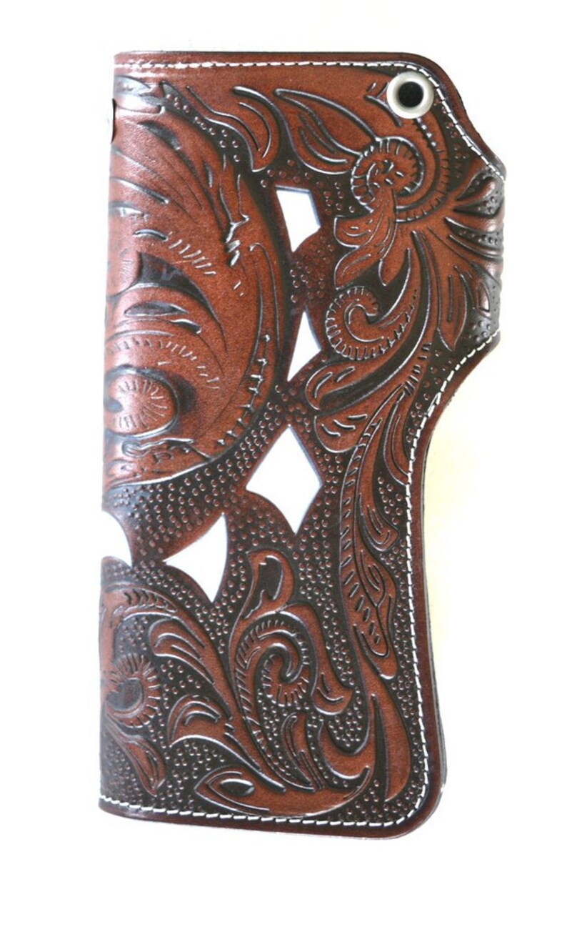 Puede incluir: Una cartera de cuero marr&oacute;n con un dise&ntilde;o floral tallado. La cartera tiene costuras blancas alrededor de los bordes y un cierre de presi&oacute;n plateado.