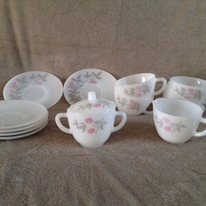 May include: A white tea set with a pink and grey floral design. The set includes a creamer and sugar bowl, four cups, and four saucers.