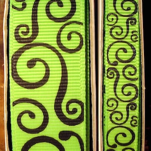 May include: Two spools of green and black ribbon with a swirl pattern. The ribbon is on a white background.