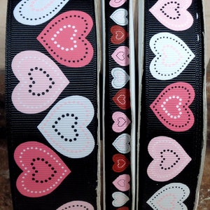 Peut inclure: Trois rouleaux de ruban noir avec un motif répété de cœurs roses et blancs avec des pois noirs.