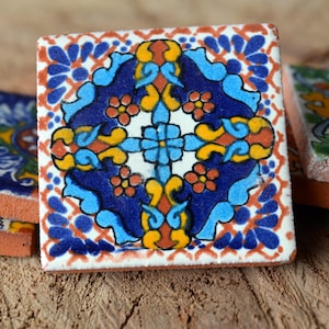 Könnte beinhalten: Ein Satz von vier bunten Keramikfliesen mit komplizierten Blumenmustern in Blautönen, Gelb, Rot und Grün. Die Fliesen haben ein rustikales, handgemachtes Aussehen und wären perfekt, um einem Zuhause einen Hauch von mexikanischem Stil zu verleihen.