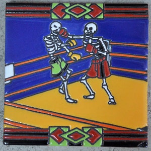 Può includere: Due scheletri con guantoni da boxe e pantaloncini stanno combattendo su un ring di boxe. Il ring è delimitato da nero e arancione su uno sfondo blu. Gli scheletri indossano pantaloncini verdi e rossi. La piastrella è decorata con un bordo nero, rosso e verde.