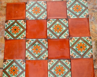 May include: A set of 12 terracotta tiles with a geometric pattern in shades of green, white, and orange. The tiles feature a floral design with a central flower surrounded by smaller flowers and leaves.