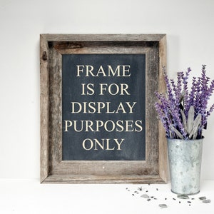 May include: A rustic wooden framed sign with the text "FRAME IS FOR DISPLAY PURPOSES ONLY" on a dark blue background. A galvanized metal bucket holds purple lavender sprigs. Small gray stones are scattered near the bucket.