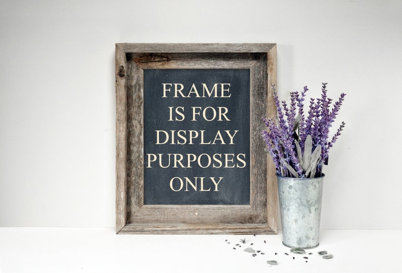 May include: A rustic wooden framed sign with the text "FRAME IS FOR DISPLAY PURPOSES ONLY" on a dark blue background. A galvanized metal bucket holds purple lavender sprigs. Small gray stones are scattered near the bucket.