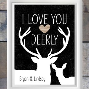 May include: Black and white print with a silhouette of two deer, one with antlers. The text "I love you deerly" is above the deer with a brown heart in the middle of the text. The names "Bryan & Lindsay" are below the deer.