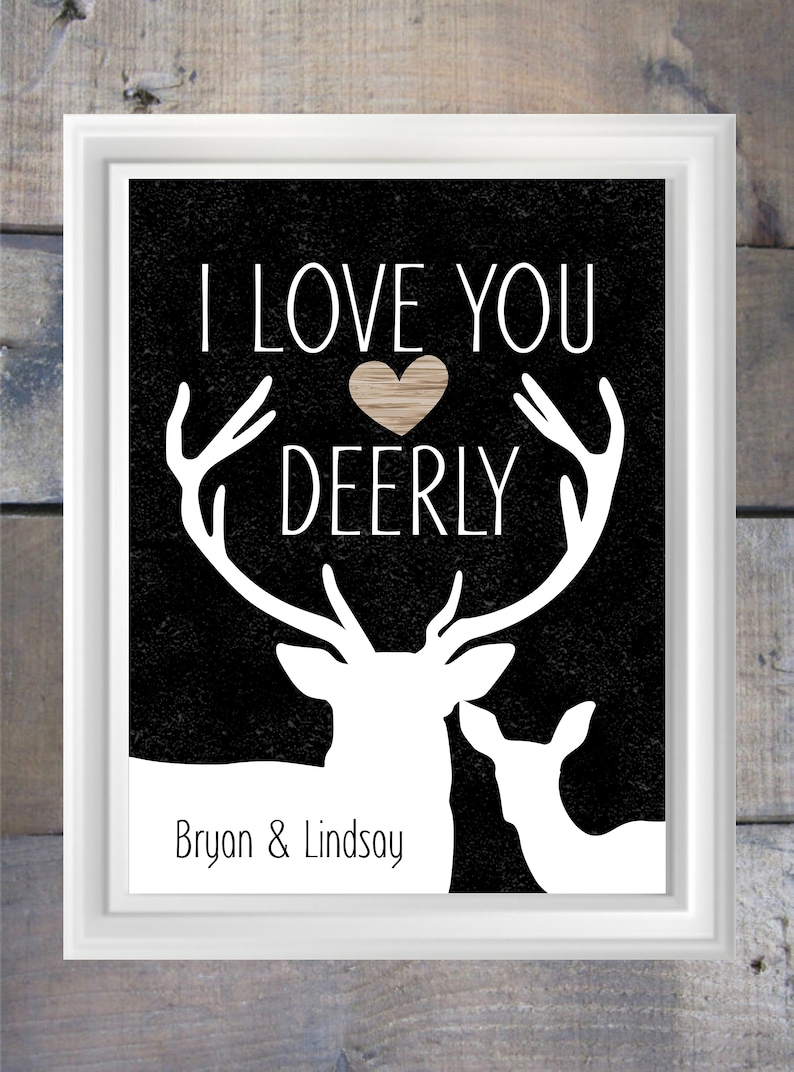 May include: Black and white print with a silhouette of two deer, one with antlers. The text "I love you deerly" is above the deer with a brown heart in the middle of the text. The names "Bryan & Lindsay" are below the deer.