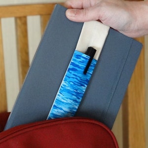 May include: A blue and white patterned fabric pen holder is attached to a gray notebook. The notebook is closed and the pen holder is tucked inside the cover.