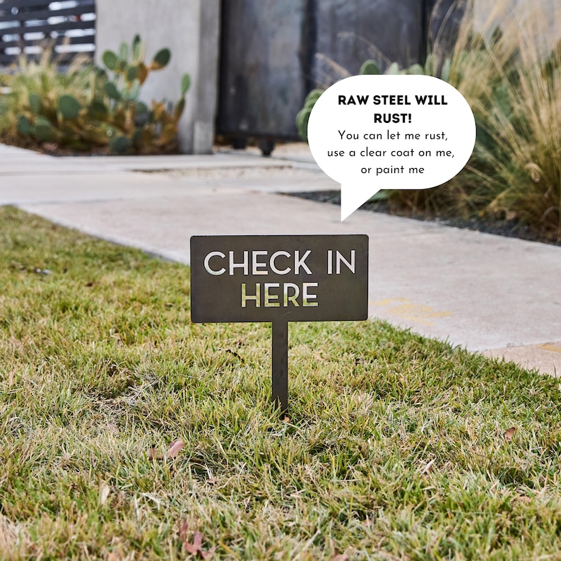 May include: A rectangular raw steel garden sign on a stake with the text CHECK IN HERE. A speech bubble above the sign reads: RAW STEEL WILL RUST! You can let me rust, use a clear coat on me, or paint me. The sign is dark gray and metallic.