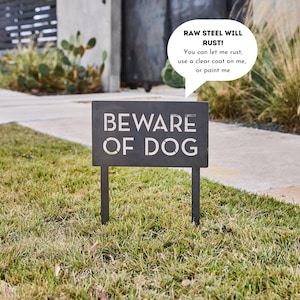 May include: A black metal sign with the words "BEWARE OF DOG" in white lettering. A speech bubble above the sign reads "RAW STEEL WILL RUST! You can let me rust, use a clear coat on me, or paint me."