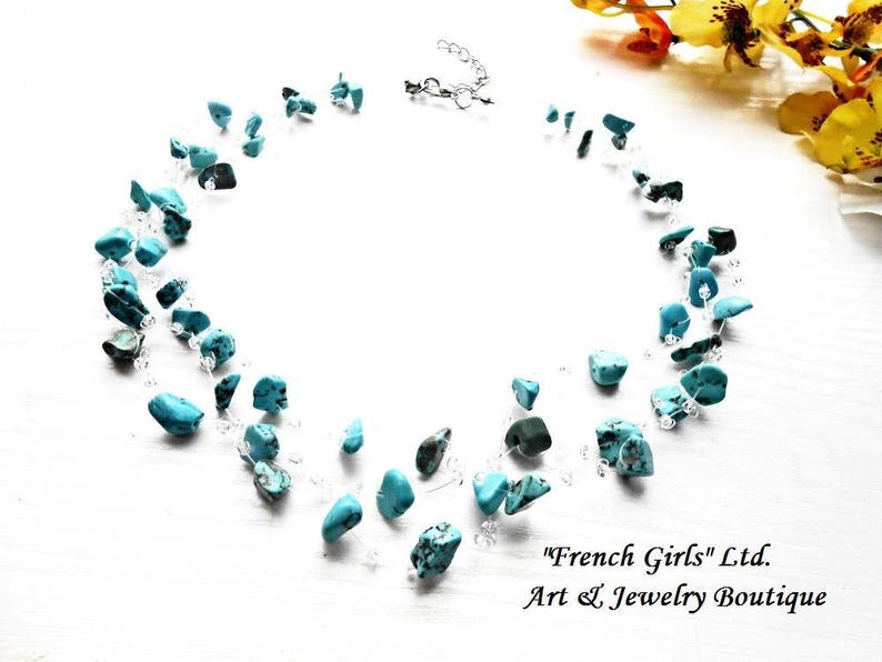 May include: A turquoise gemstone necklace with a silver chain. The necklace is made of small, irregular shaped turquoise stones and is strung on a delicate silver chain. The necklace is displayed on a white background.