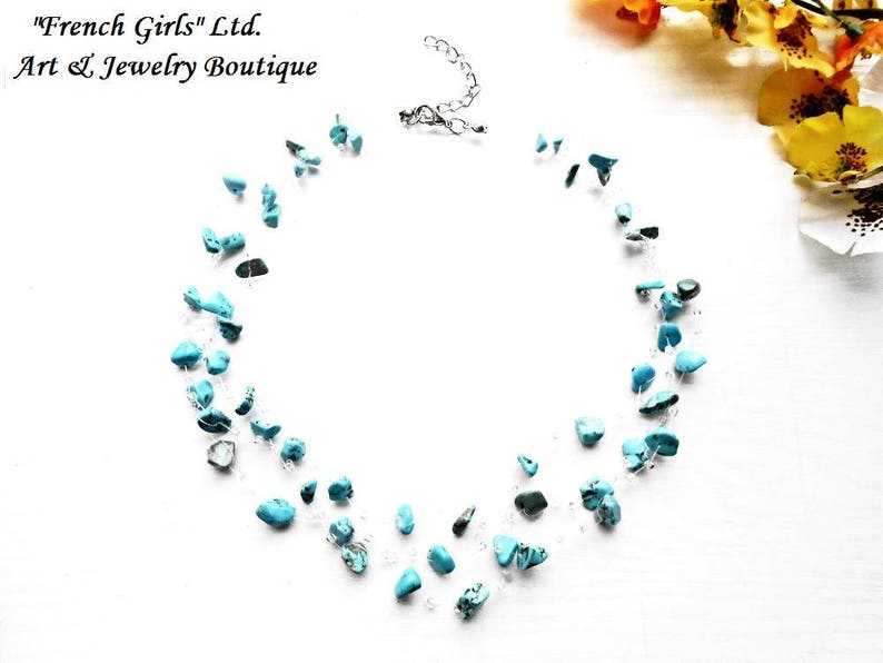 May include: A turquoise gemstone necklace with a silver clasp. The necklace is made of small, irregular shaped turquoise stones strung on a clear thread.